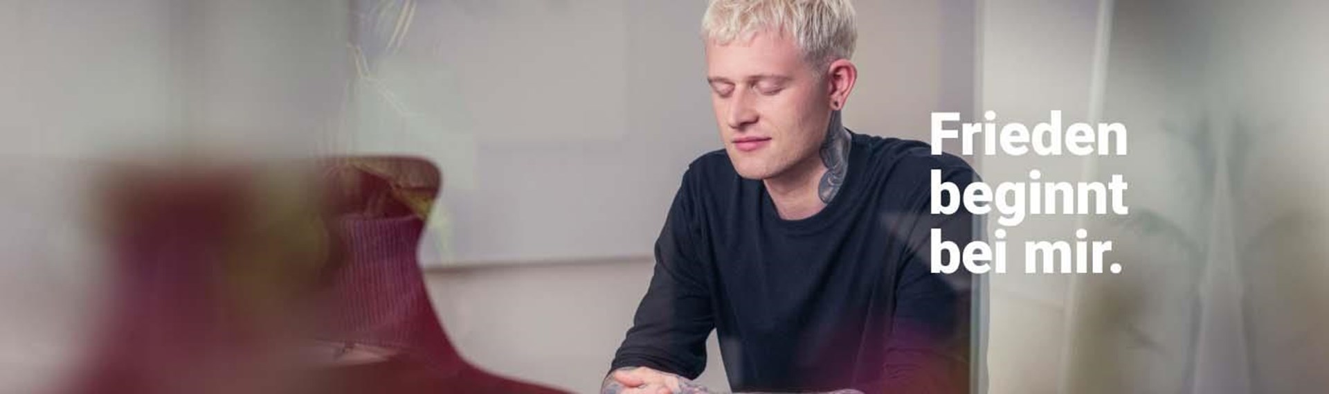 Ein junger Mann mit kurzen blondierten Haaren mit der Aufschrift "Friede beginnt bei mir."